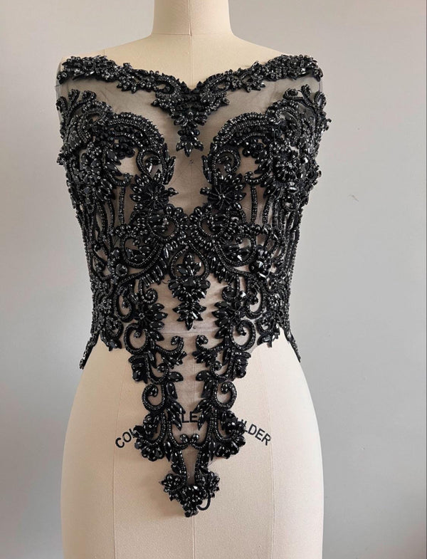 Black lace top on a mannequin against a plain background