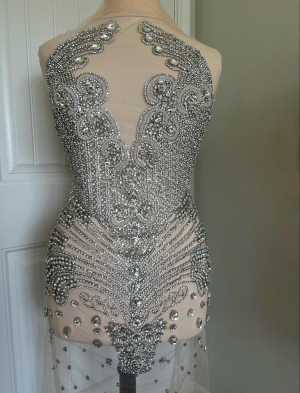 Elegant dress with intricate silver beadwork on a plain background